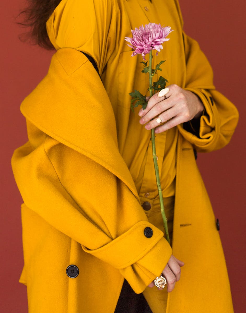 Woman Wearing Yellow Trench Coat While Holding Purple Flower